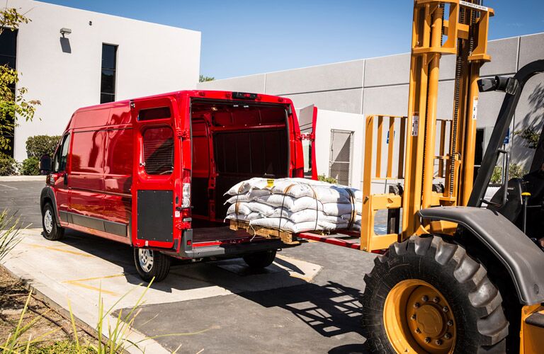 red 2016 Ram ProMaster cargo van being loaded with a forklift