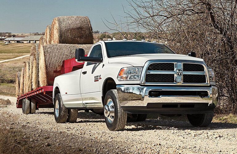 white 2018 Ram 3500 towing hay bales on a dirt road