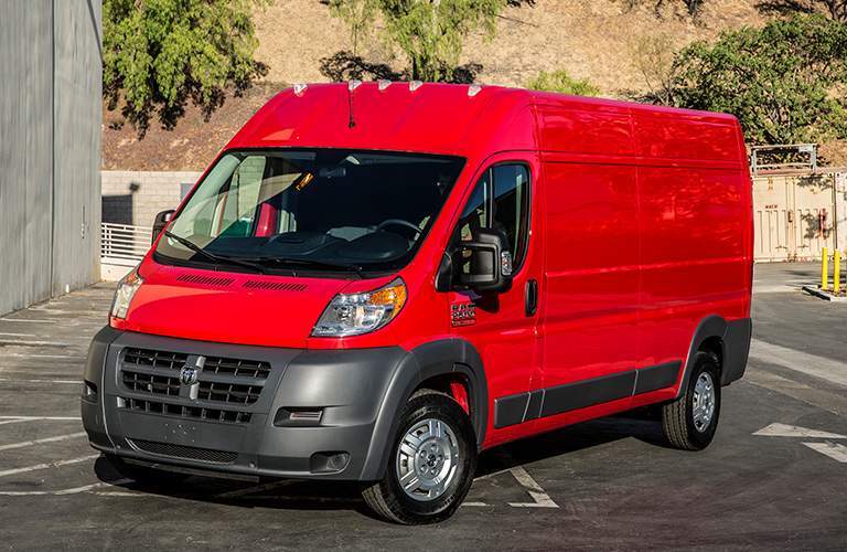 side view of a red 2018 Ram ProMaster in a parking lot with a hill in the background