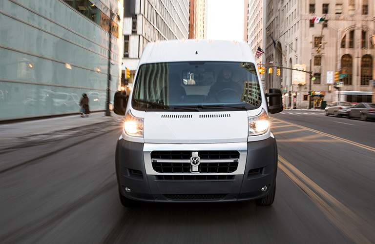 front view of a white 2018 Ram ProMaster driving down a city street