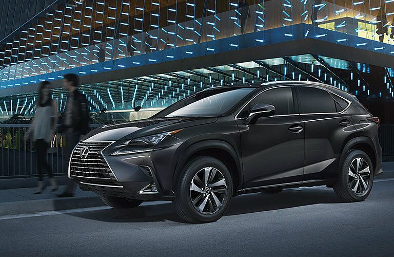 Silver Lexus NX parked in front of modern building at night Silver Lexus NX parked in front of modern building at night