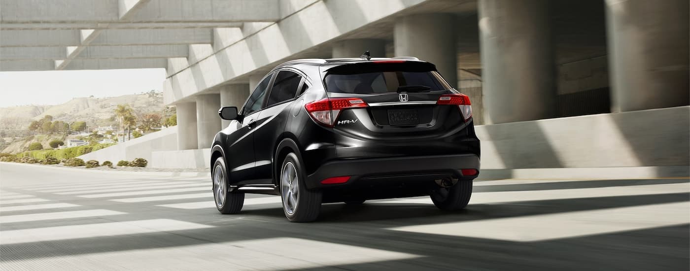 A black 2022 Honda HR-V EX-L is driving through a city.