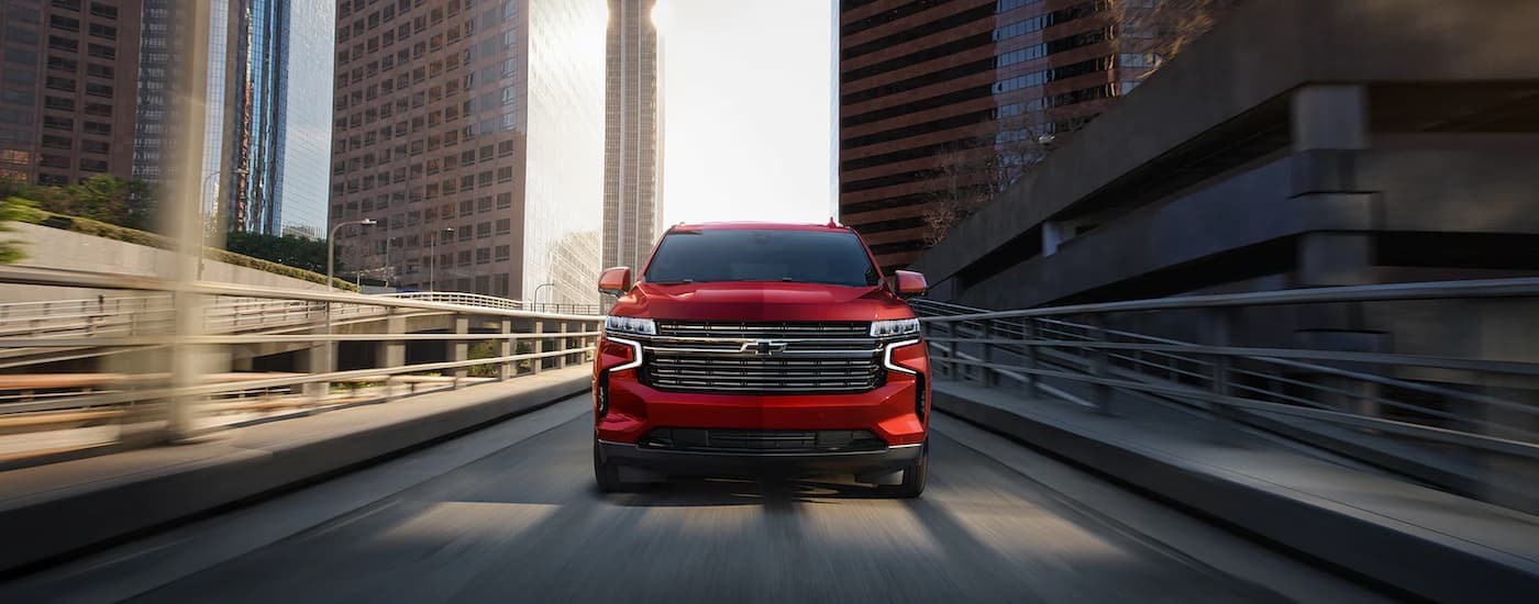 A red 2023 Chevy Tahoe is driving on a highway after leaving a dealer with SUVs for sale in Jersey City.