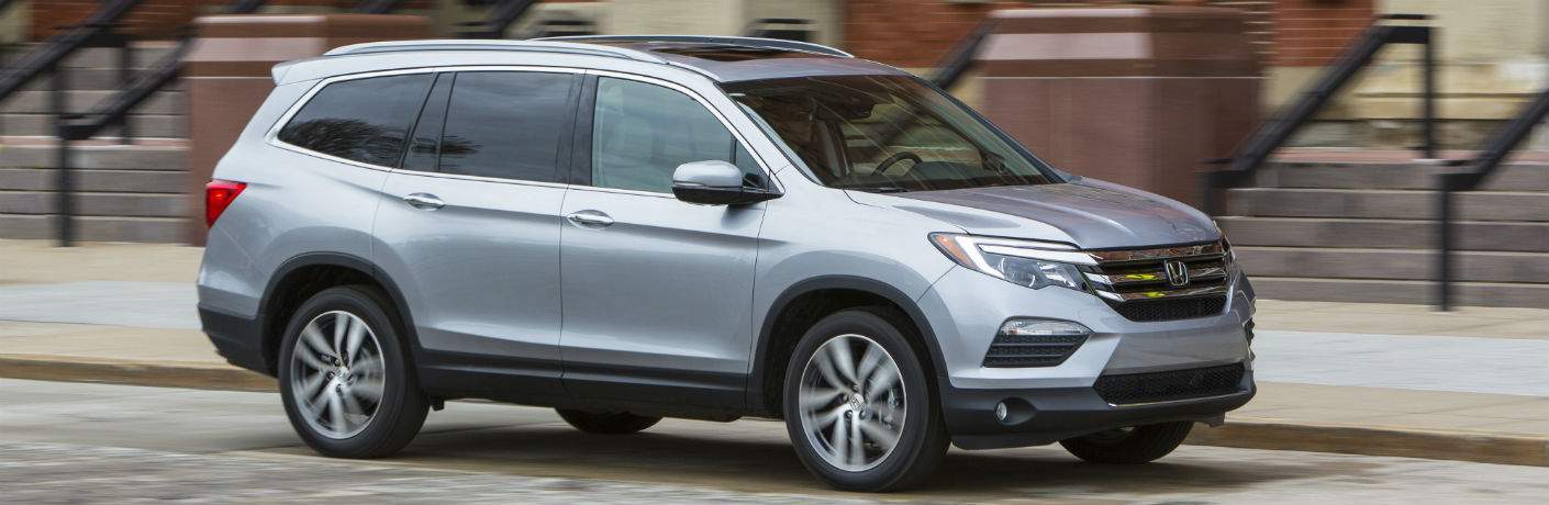 side view of a 2018 Honda Pilot with a blurred city wall background