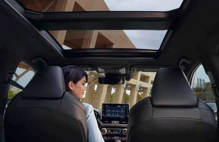 A woman sitting in the 2022 Toyota RAV4 Hybrid during day time.