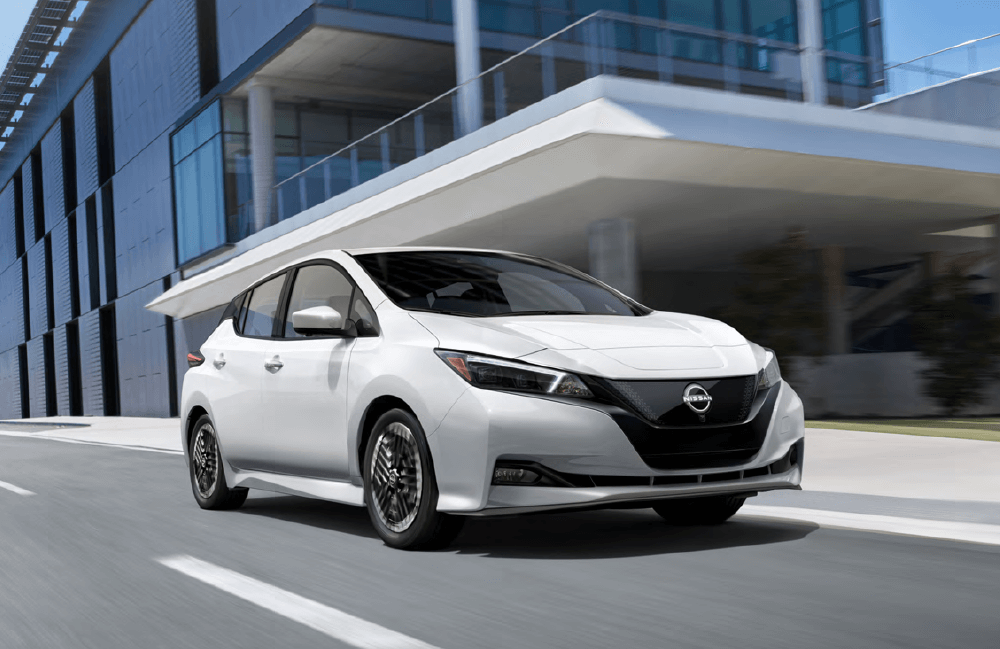 Nissan LEAF front view driving on road in front of building Nissan LEAF front view driving on road in front of building