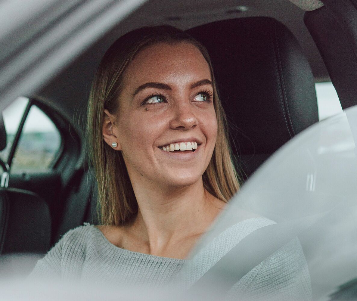 Woman smiling in the window of a car Woman smiling in the window of a car