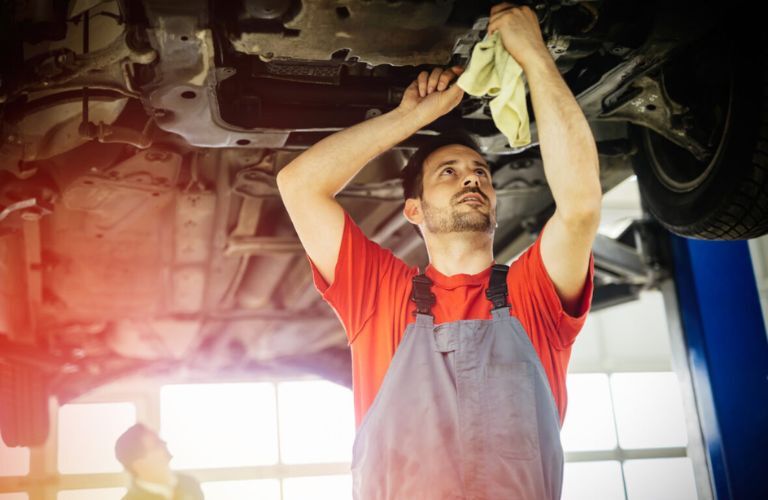 Technician inspecting a vehicle's underside