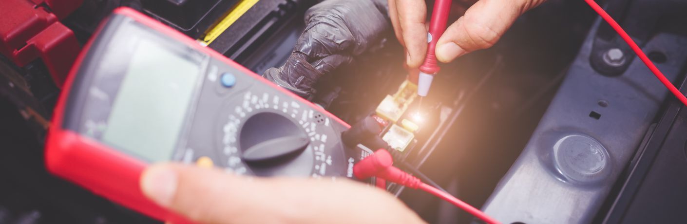 Technician using jumper cables to check battery