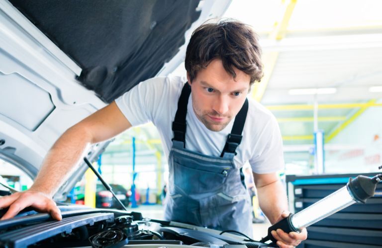 technician looking under the hood of a vehicle