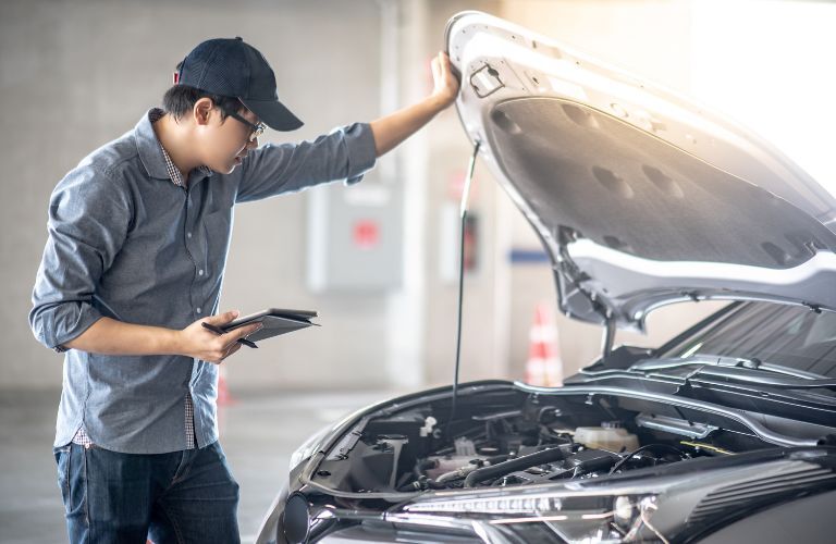 technician looking under the hood of a vehicle