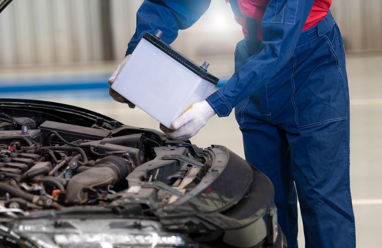 technician installing battery in a vehicle