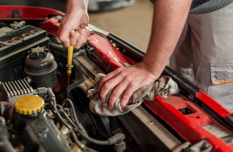 technician checking oil level in car