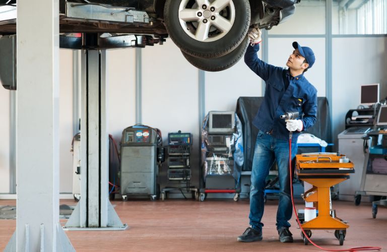 Technician servicing the underside of the vehicle