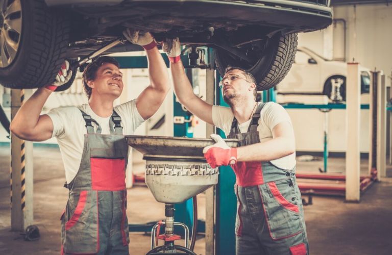 Technicians inspecting fluids under the vehicle