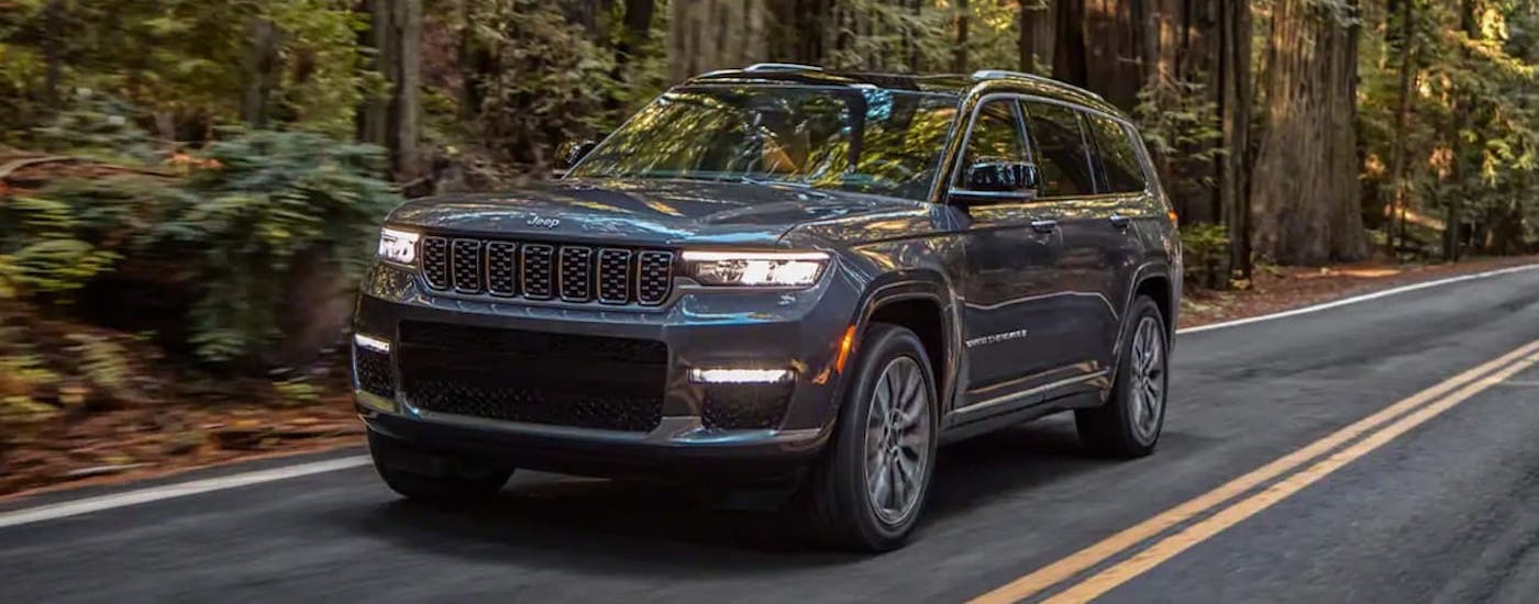 Grey 2021 Jeep Grand Cherokee L driving down a road.