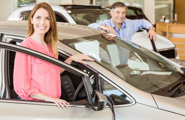 man and a woman standing by a car pleased with their car-buying experience