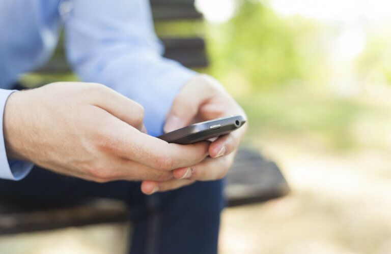man using a phone, possibly to interact with his car through a connectivity service