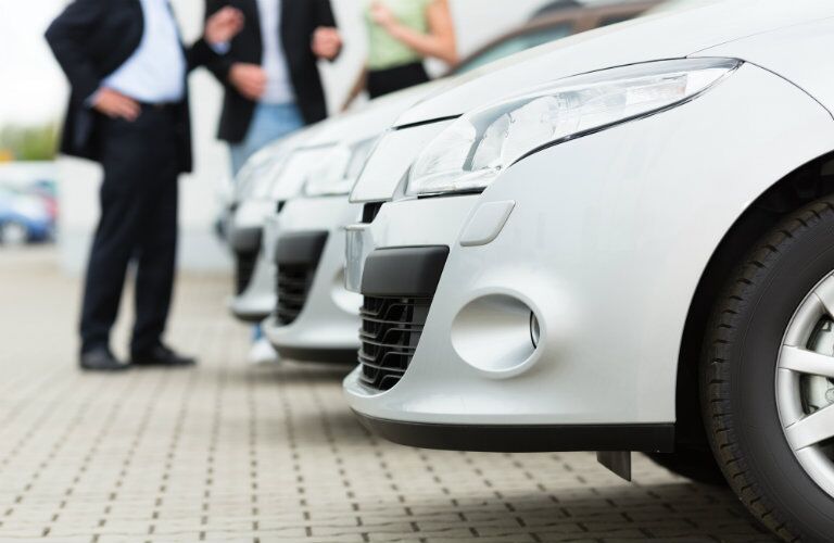 Row of white cars with people considering getting a new one