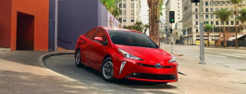 front view of a red 2022 Toyota Prius driving on a road