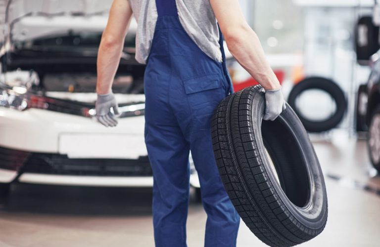 technician carrying a tire