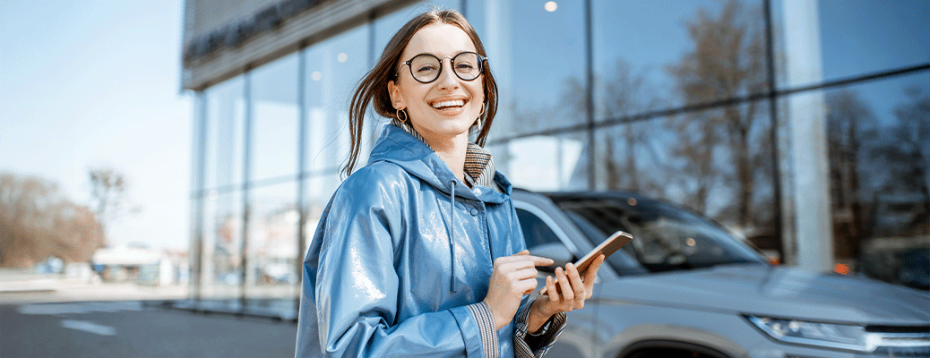 a person in a dealership parking lot holding a phone