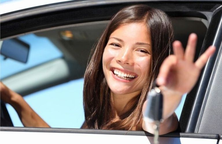 Person smiling and showing a car key