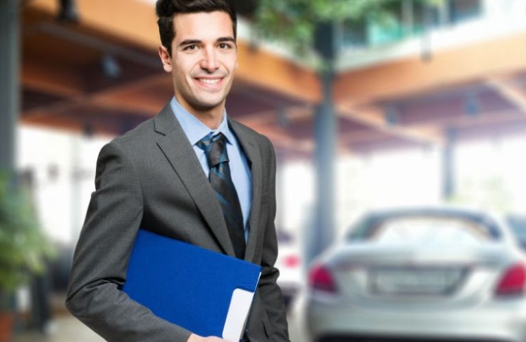 a salesman holding a file at a dealership