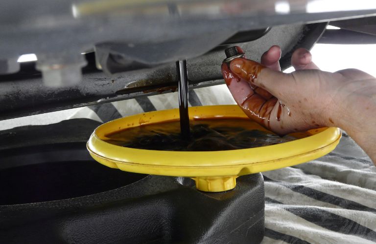 Close up image of a hand draining engine oil into a filter