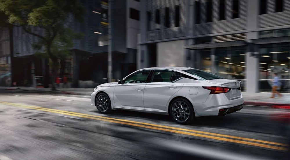 A silver 2024 Nissan Altima driving on a wet city street