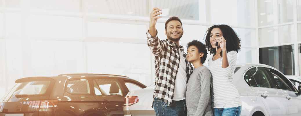 family posing with a key at a dealership