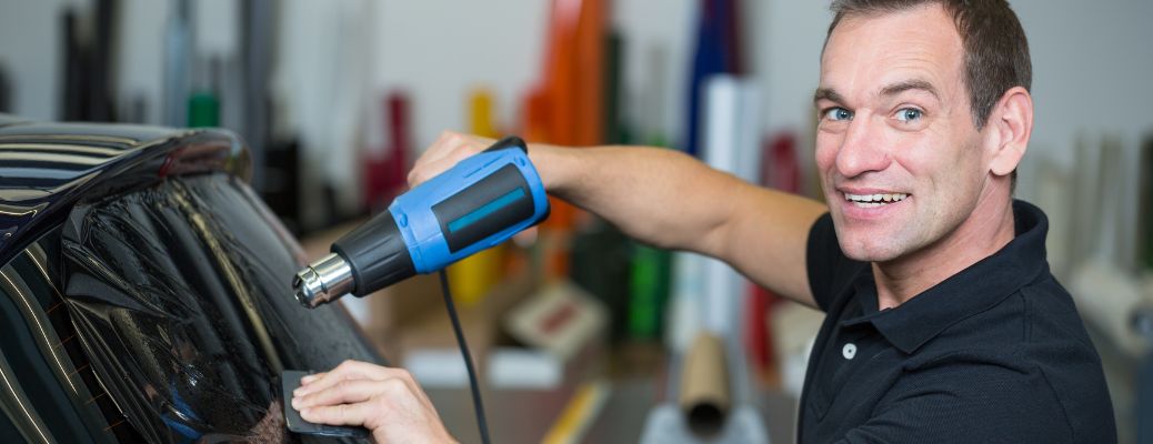 A mechanic tinting a window