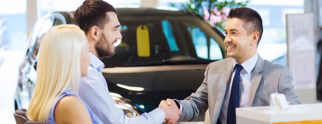 Salesman talking to a couple at a dealership