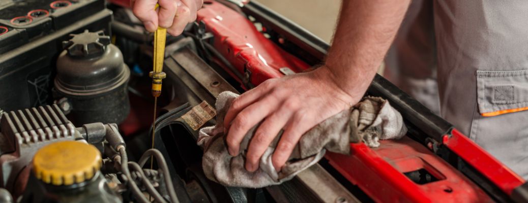 hnads of a mechanic checking oil