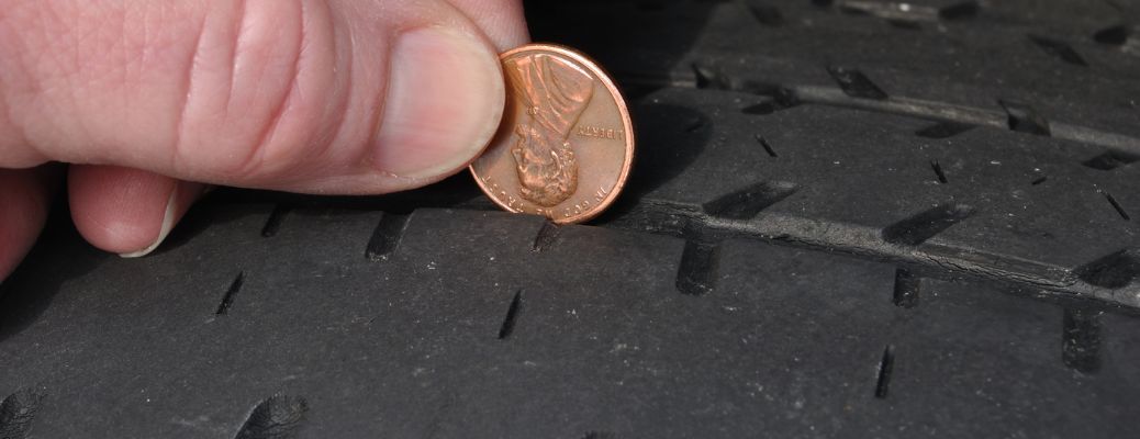 people using a penny to measure tire tread depth