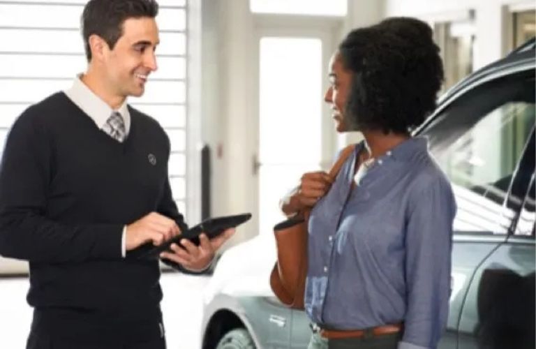 two people at a Mercedes-Benz dealership by a car