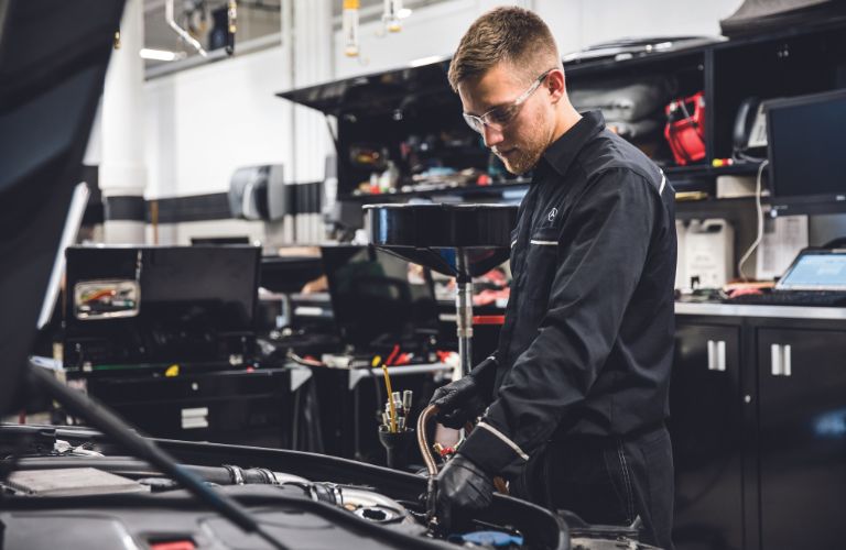 A man working on a Mercedes-Benz vehicle at a service center