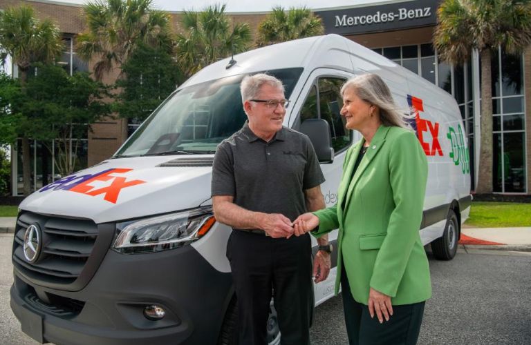Two people posing in front of Mercedes-Benz Sprinter