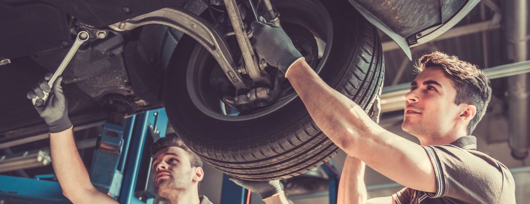 Two mecahnics working on a vehicle