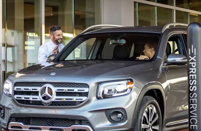 A smiling man talking to another man inside a car