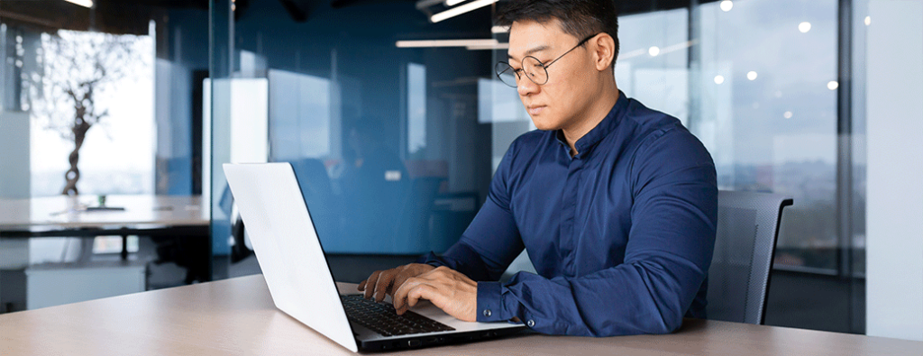 a person at a desk using a white laptop