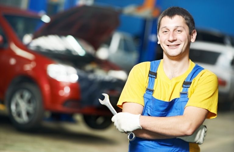 A smiling mechanic holding a tool