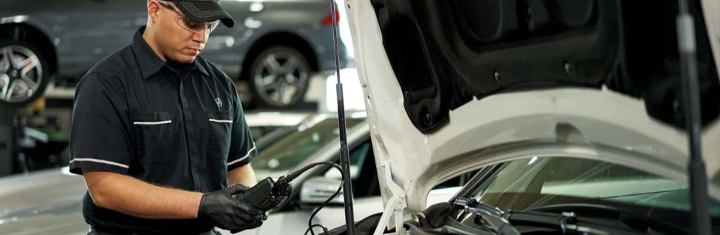 a man checking the engine of a Mercedes-Benz car