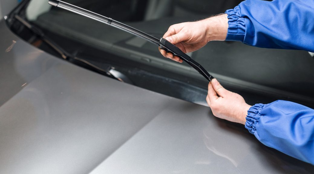 Technician is changing windscreen wipers on a car station