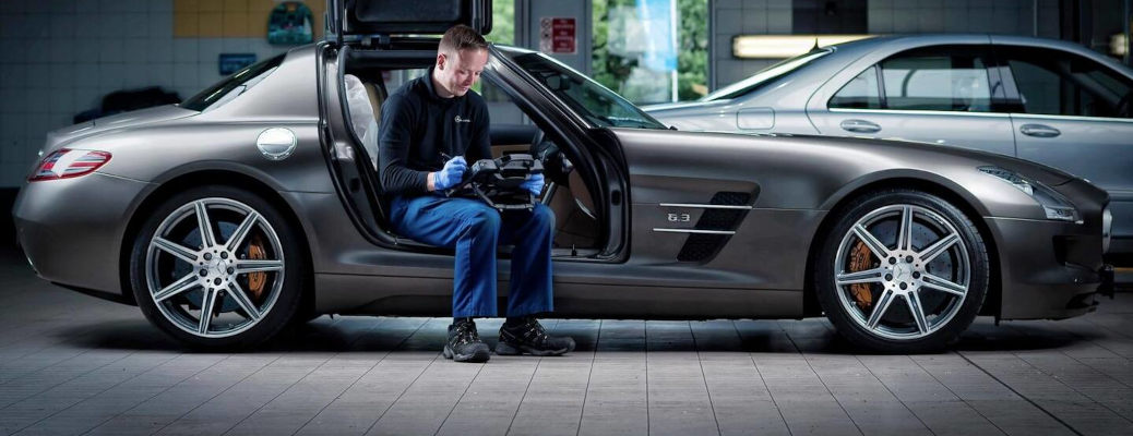 A Mercedes technician performing routine summer maintenance on a C 63 sedan.