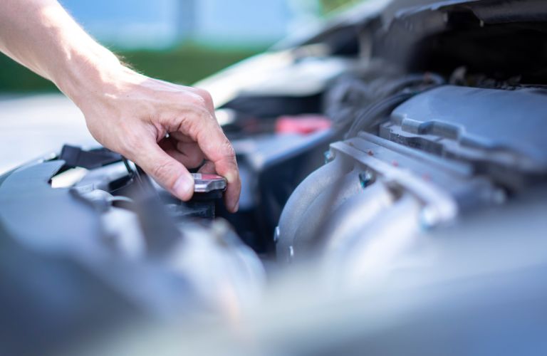 Hands of a man checking the engine of a vehicle