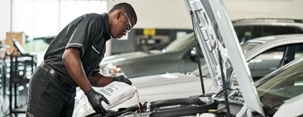 Service professional putting fluid into a vehicle