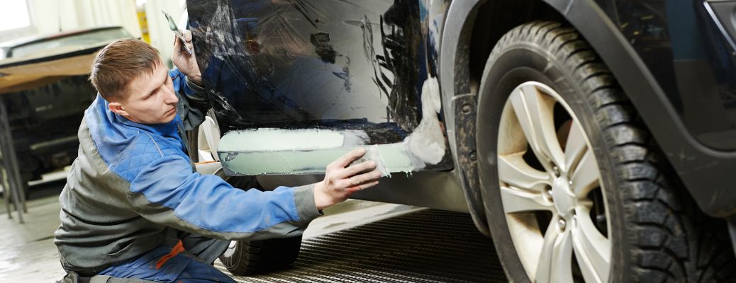 Mechanic preparing car panels for painting