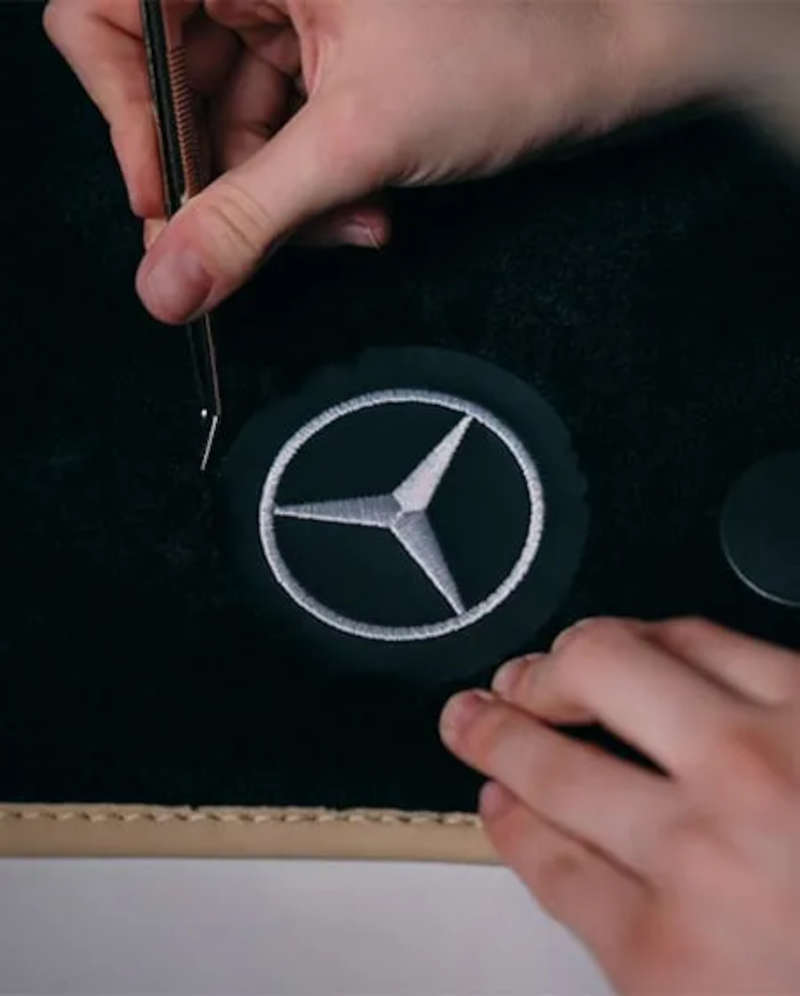 MANUFAKTUR custom stitching being applied to a Mercedes-Benz deep pile floor mat.