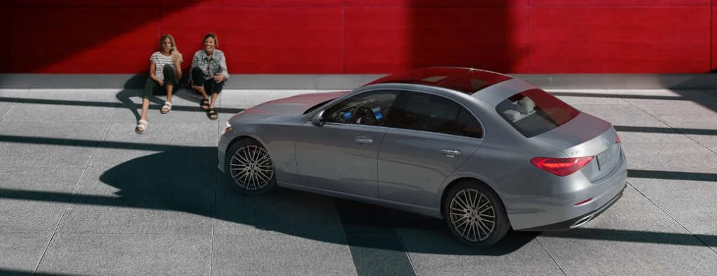 Two women sitting near a pre-owned Mercedes-Benz